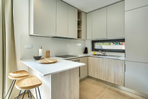 a kitchen with white cabinets and a counter and stools at Villa Sponza in Medulin