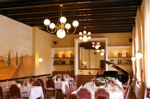 uma sala de jantar com mesas e cadeiras e um lustre em In Piazza em Bad Klosterlausnitz