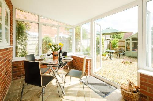 a conservatory with a table and chairs and windows at 8 Saxonfields in Snape