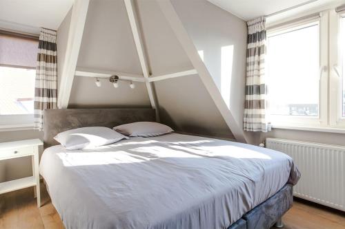 1 dormitorio con 1 cama grande con sábanas y almohadas blancas en Zeehuis Zandvoort, en Zandvoort