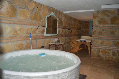 a bath tub in a room with a stone wall at Apartamentos El Aljibe Relax Tourist Cordoba in Córdoba