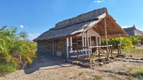 a small hut with a thatched roof on a field at Chemka Paradise Eco Lodge in Boma la Ngombe