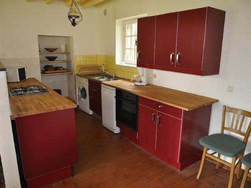 une cuisine avec des armoires rouges et un comptoir dans l'établissement clos du Mont maison sur falaise, à Étretat