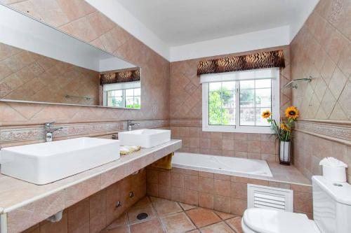 een badkamer met 2 wastafels, een bad en een spiegel bij Villa Guapa in San Miguel de Abona