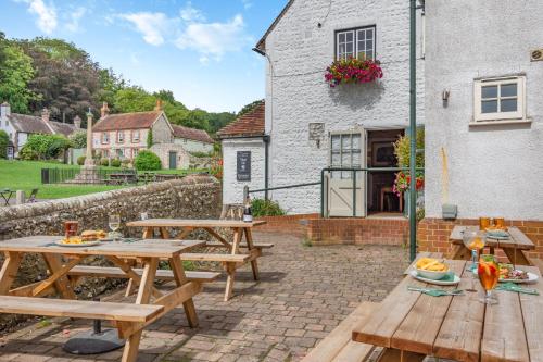 a patio with wooden picnic tables in front of a building at Tiger Inn - Grace in Eastbourne