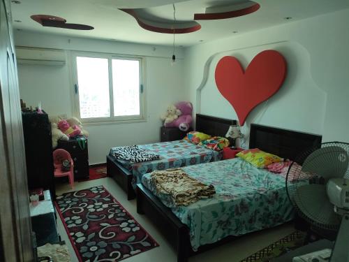a bedroom with two beds with a heart on the wall at شقه فاخره للايجار المفروش الابراهيميه على البحر in Alexandria