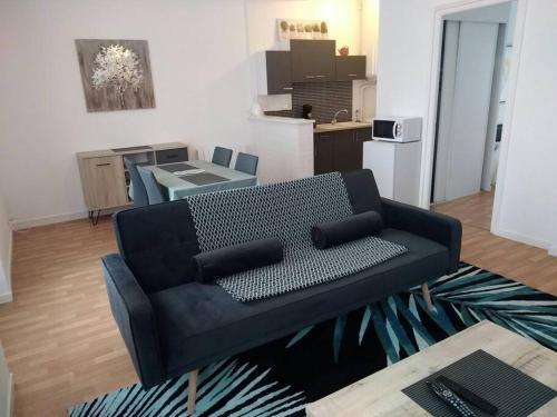 - un canapé noir dans le salon avec une cuisine dans l'établissement DESTELLE APPART proche gare, à Saint-Brieuc