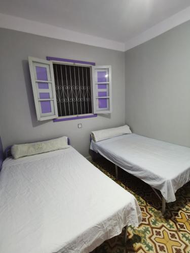 2 Betten in einem Zimmer mit Fenster in der Unterkunft فندق آل الشيخ أحمد in Targuist