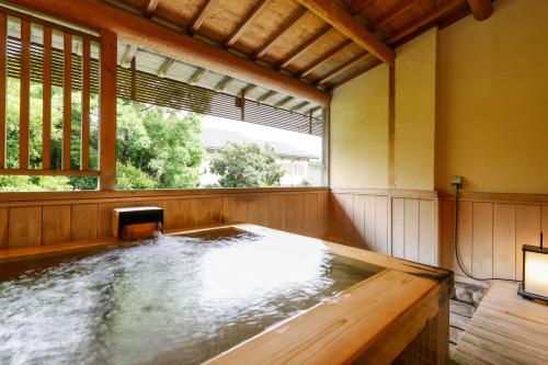a hot tub in a room with a window at Kaikatei Hanagozen in Kyotango