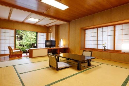 a room with a table and chairs and windows at Kaikatei Hanagozen in Kyotango