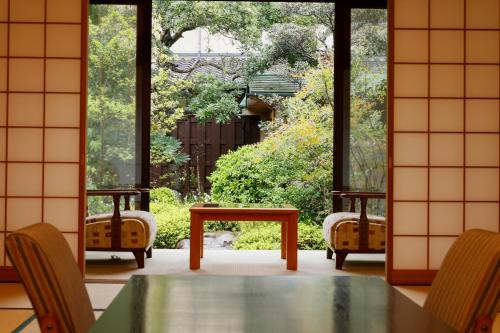a table and chairs in a room with a large window at Kaikatei Hanagozen in Kyotango