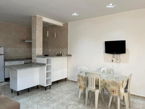 a kitchen with a table with chairs and a tv on the wall at Maison Eline in Harqalah