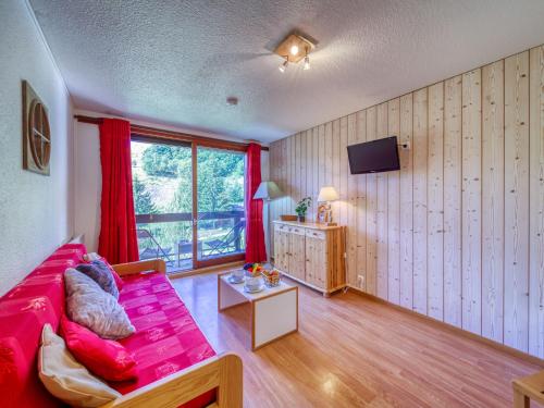 sala de estar con sofá rojo y ventana en Apartment Pegase Phenix-6, en Le Corbier