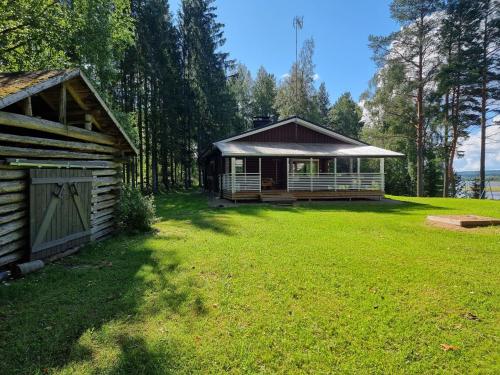 a house with a large yard next to a cabin at Holiday Home Saarenpää by Interhome in Koivisto
