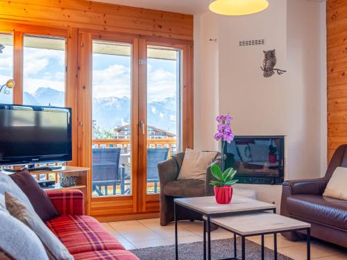 een woonkamer met een bank en een tv bij Apartment Les Chouettes 11 by Interhome in Nendaz