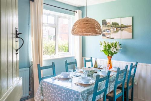 niebieska jadalnia ze stołem i krzesłami w obiekcie Fairstead Cottage by Big Skies Cottages w mieście Holt