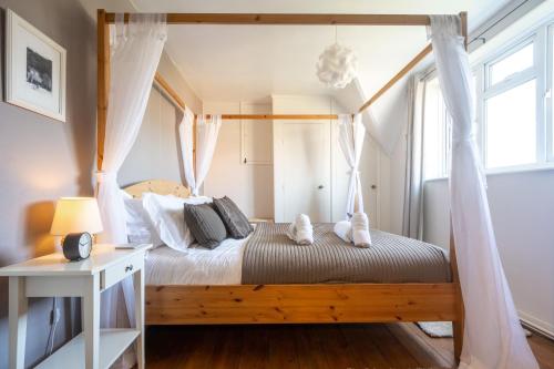 sypialnia z łóżkiem z baldachimem i białymi zasłonami w obiekcie Fairstead Cottage by Big Skies Cottages w mieście Holt