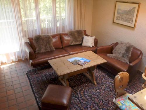 een woonkamer met een bruine leren bank en een salontafel bij Apartment Vitalis by Interhome in Zermatt