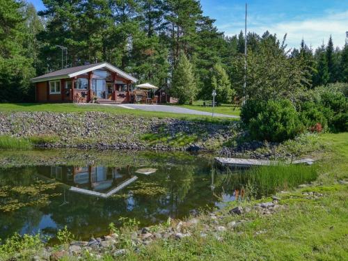 a log cabin with a pond in front of it at Holiday Home Kannelpirtti 1 by Interhome in Puromäki