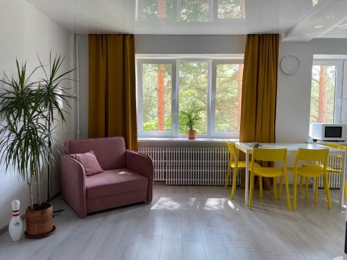 a living room with a chair and a table at Sunny apartment with lake and forest view in Visaginas