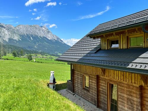 ein Holzhaus mit einem Berg im Hintergrund in der Unterkunft Chalet Grimmingblickhütte - GBM301 by Interhome in Unterlengdorf