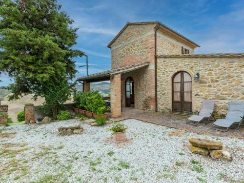 an external view of a stone house with two chairs at Holiday Home Villa Caggio-4 by Interhome in Volterra