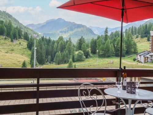 - une table avec un parasol rouge sur le balcon dans l'établissement Studio Rosablanche D13 by Interhome, à Siviez