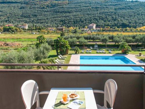 a balcony with a table and chairs and a swimming pool at Apartment Comfort by Interhome in Riva del Garda