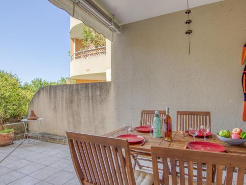 une table en bois avec des plaques rouges sur une terrasse dans l'établissement Apartment Le Stadium-7 by Interhome, à Saint-Cyr-sur-Mer