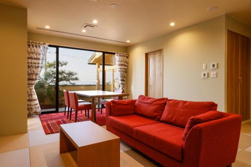 a living room with a red couch and a table at Kaikatei Hanagozen in Kyotango