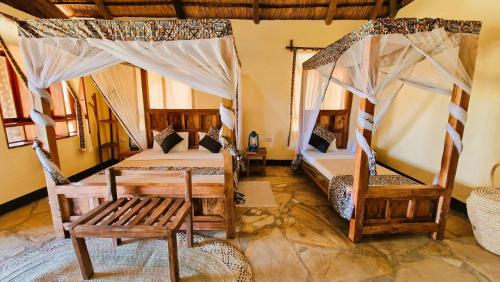 a room with two beds and a bench in it at Africa Safari Lake Natron in Mtowabaga