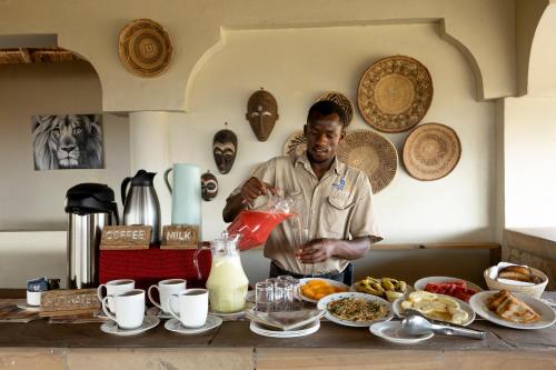 un hombre parado frente a una mesa de comida en Africa Safari Lake Natron en Mtowabaga