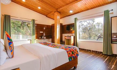Kanari Mussoorie by Red Finch Hotels في موسوري: غرفة نوم بسرير كبير ونافذة كبيرة