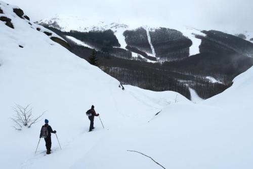 two people are skiing down a snow covered slope at Aera - Glass cabins in Tromsø
