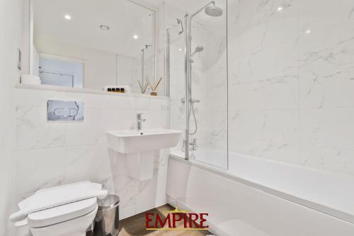 a white bathroom with a sink and a shower at Lovely One Bedroom Apartment on Broad Street! in Birmingham