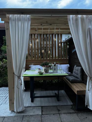 a patio with a table and curtains on a deck at Apartment Wohlfühlplatzl - urgemütlich & ruhig in Vogtareuth