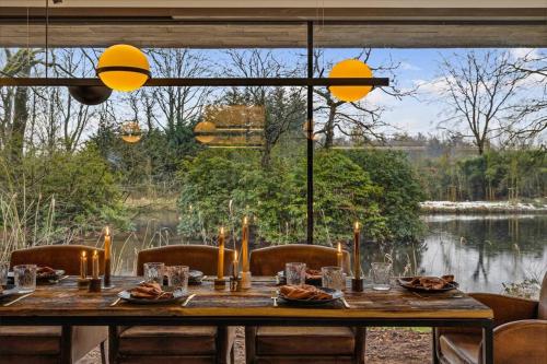 a dining room table with a view of a lake at Stylish lakehouse in idyllic, private green scenery in Stekene