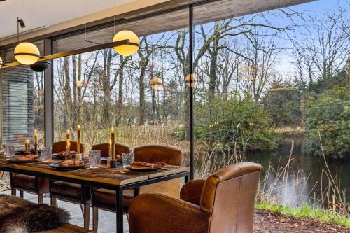 a dining room with a table and a view of a river at Stylish lakehouse in idyllic, private green scenery in Stekene