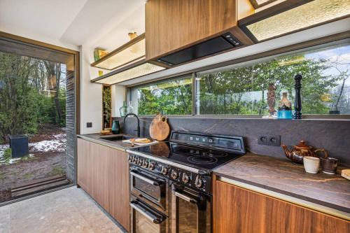 a kitchen with a stove top oven next to a window at Stylish lakehouse in idyllic, private green scenery in Stekene