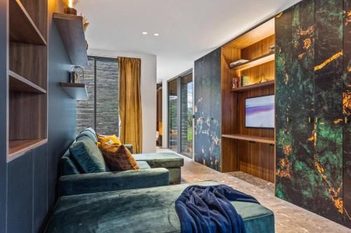 a living room with a couch and a tv at Stylish lakehouse in idyllic, private green scenery in Stekene