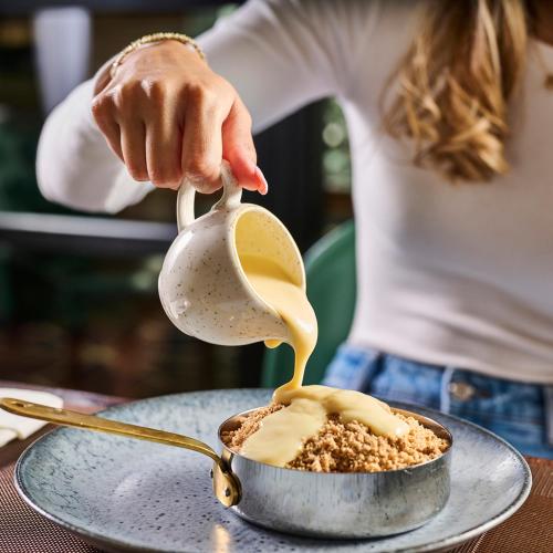 a woman pouring peanut butter into a bowl of food at Genting Hotel & Spa at Resorts World Birmingham in Bickenhill