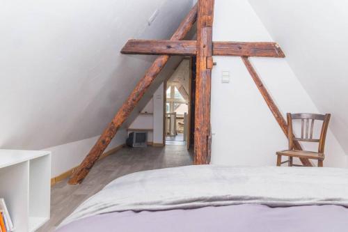 une chambre avec un lit et une chaise dans un grenier dans l'établissement charmant appartement alsacien, à Ribeauvillé