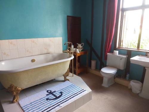 a bathroom with a tub and a toilet and a sink at The Swan Inn in Harwich