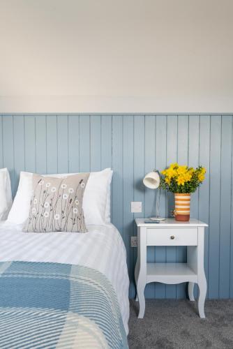 a blue bedroom with a bed and a table with a lamp at Ty Ffynnon B&B in Tenby