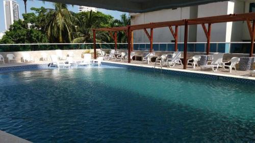 a large swimming pool with white chairs and chairs at Apartamento Mares de Cartagena in Cartagena de Indias