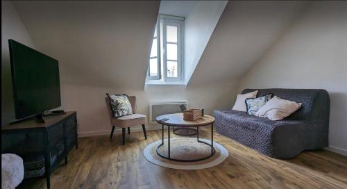 a living room with a couch and a tv at Sweet Abreuvoir in Saint-Germain-en-Laye