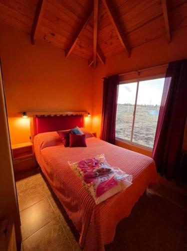 a bedroom with a bed with red sheets and a window at Cabaña Las Lavandas in Trevelín