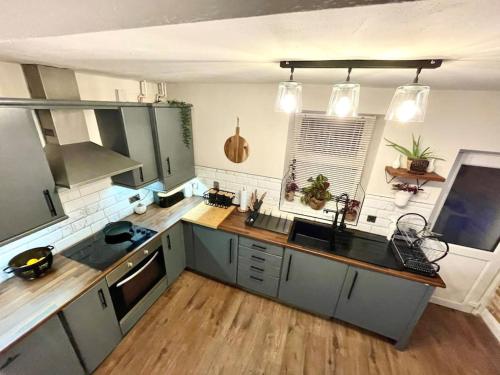 a kitchen with gray cabinets and a wooden floor at Peak District Self Catering Holiday Home in Glossop