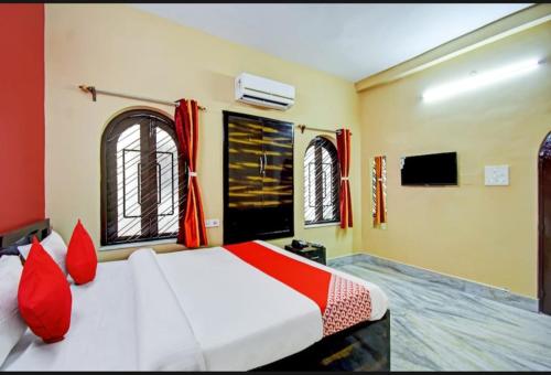 Schlafzimmer mit einem Bett mit roten Kissen und Fenstern in der Unterkunft Fantasy Stay Fusion in Kalkutta