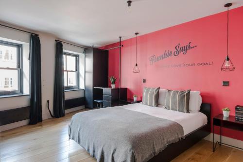 a bedroom with a large bed with a pink wall at The Instagood Apartment - Covent Garden - by Frankie Says in London